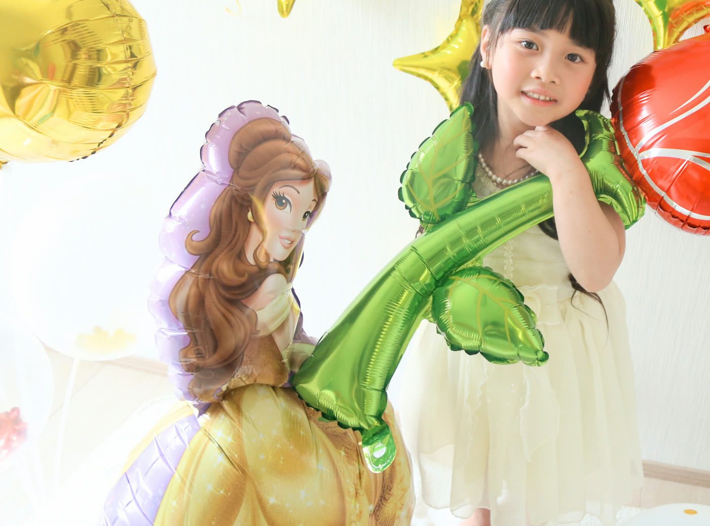 ベルのバルーンとバラのバルーンを持つ女の子