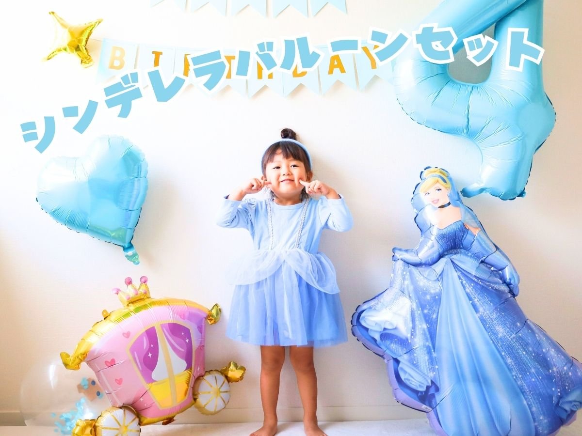 シンデレラのバルーン、馬車、ハート、王冠つきの数字バルーンとHAPPY BIRTHDAYガーランドの前に立つお子さん