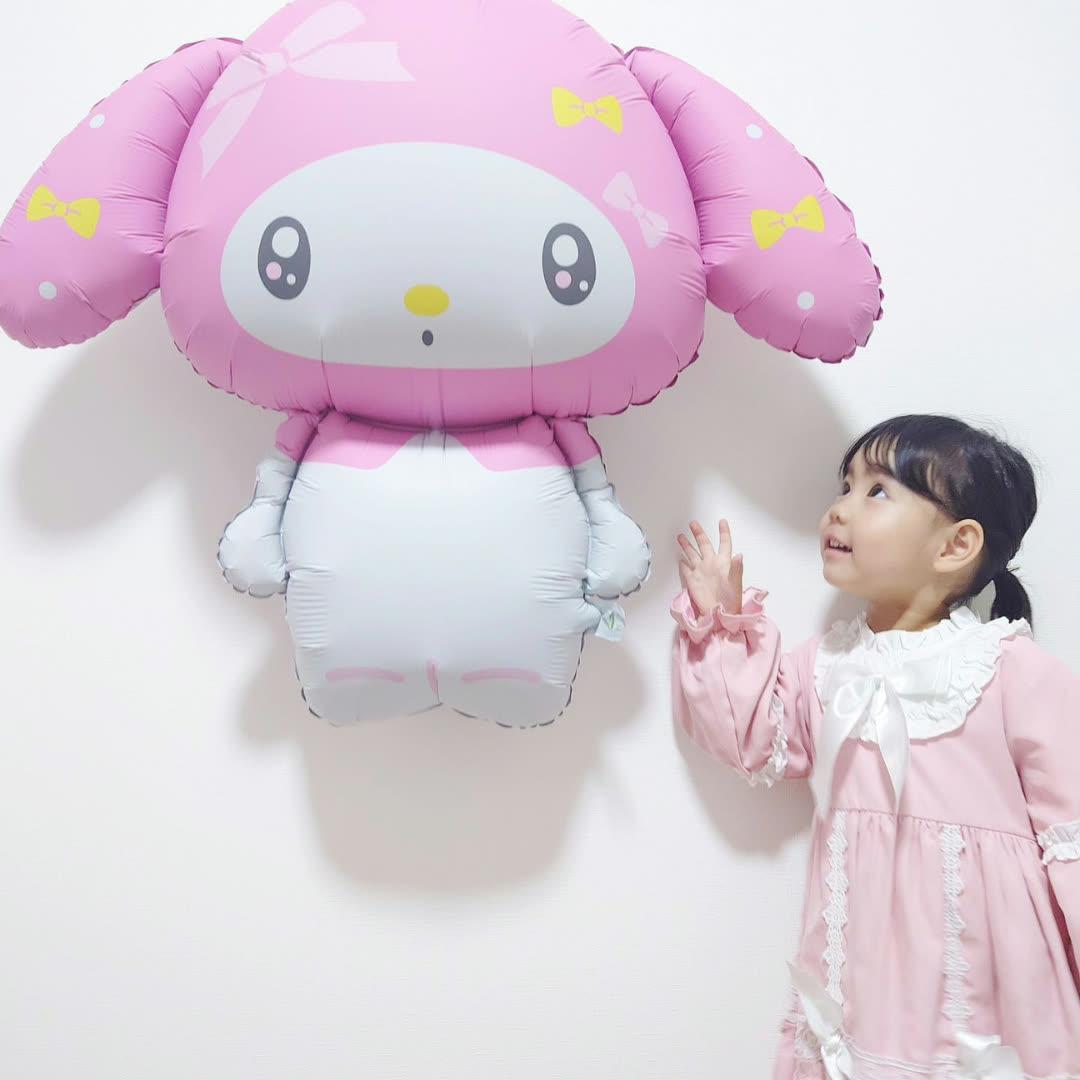 マイメロディのバルーンを見上げてタッチする女の子