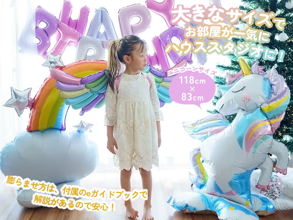 自立式のユニコーンバルーンと虹のバルーン、HAPPY BIRTHDAYの飾りの前に立つお子さん